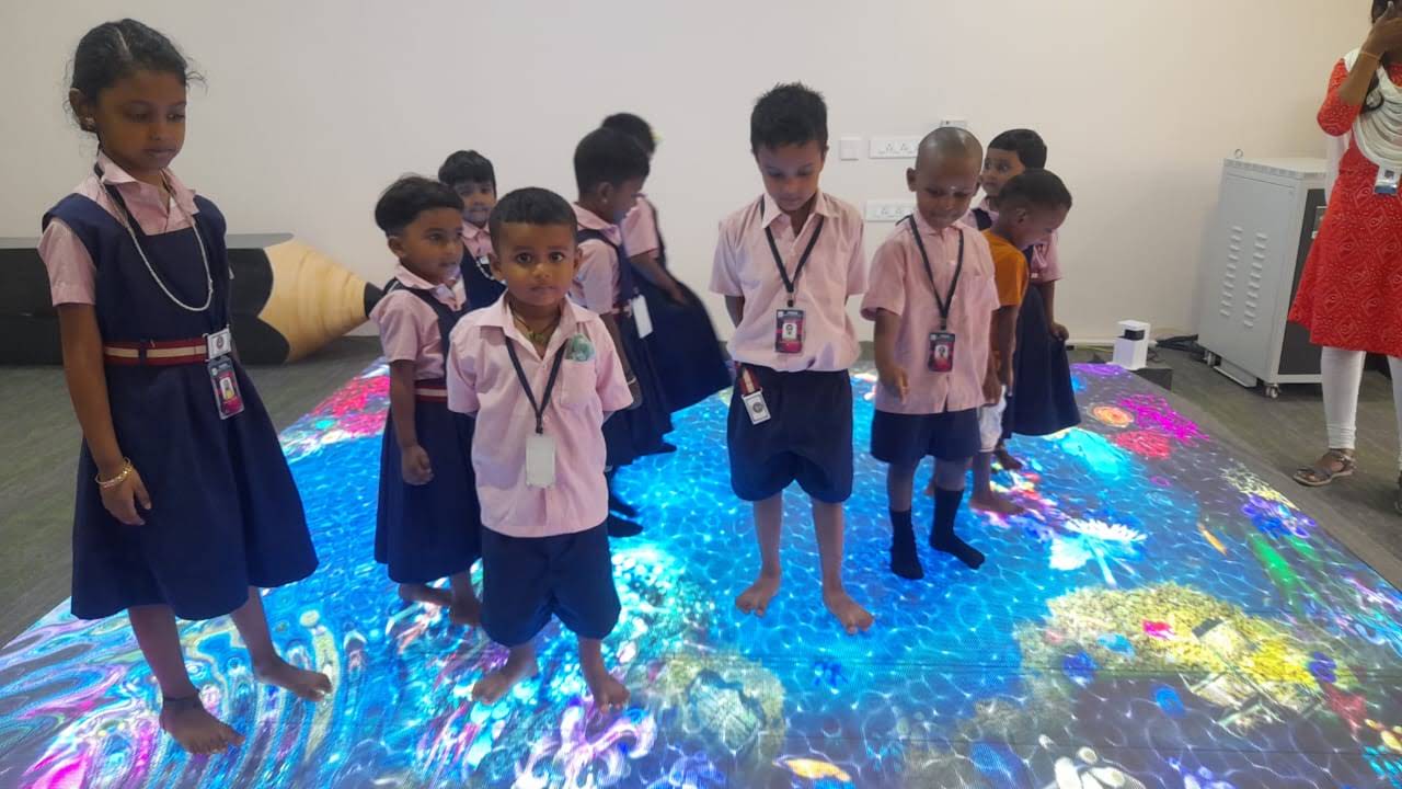 Students exploring interactive digital floor projection at Hara School