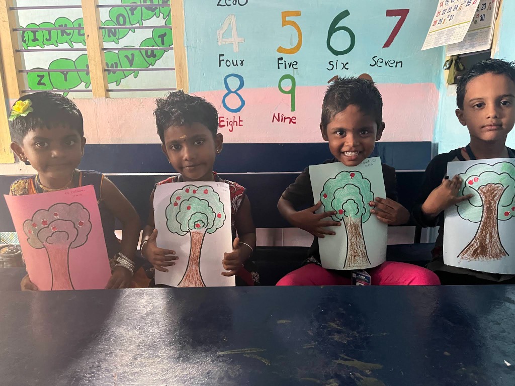Happy students displaying their tree drawings at Hara School